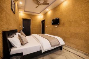 a bedroom with a bed and a tv on a wall at Hotel Saffron Diamond in Jaisalmer