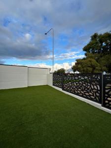 a backyard with a fence and green grass at Deni's Home in Parkes