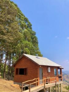 a small brick house with a porch and trees at Chalé Theo - Para momentos únicos in Camanducaia