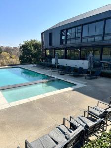 a building with a swimming pool with chaise lounges at Midrand Stylish 1Bedroom Escape in Midrand