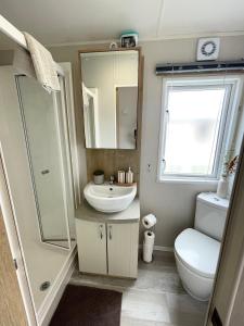 a bathroom with a sink and a toilet and a mirror at Lakeside Bliss with Fishing Peg and Hot Tub in Tattershall +42 photos