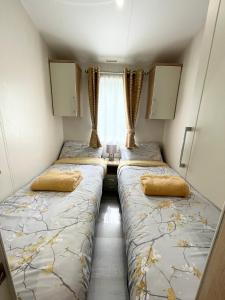 two beds in a small room with a window at Lakeside Bliss with Fishing Peg and Hot Tub in Tattershall