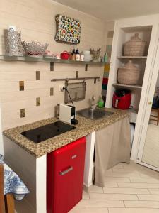 a small kitchen with a sink and a red cabinet at SnowWhite Home in Porto Ercole