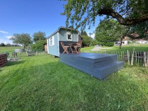 a tiny house with a porch in a yard at Genau So - Schäferwagen in Maierhöfen