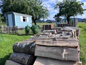 a pile of logs in a yard with a house at Genau So - Schäferwagen in Maierhöfen