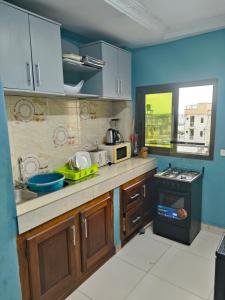 a kitchen with blue walls and wooden cabinets at Newland Sarl in Douala