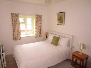 a bedroom with a white bed and a window at Culoort Cottage - Malin Head in Malin Head