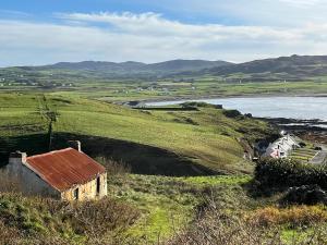 an old building on a hill next to a body of water at Culoort Cottage - Malin Head in Malin Head