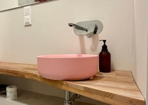 a pink bowl on a wooden counter with a sink at Apartamenty Stara Winiarnia in Wałcz