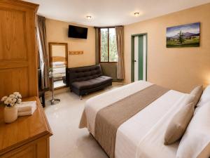 a bedroom with a bed and a chair and a couch at Hotel Galería Mediterráneo in Santa Ana Huiloac