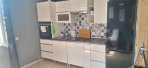 a kitchen with white cabinets and a stainless steel refrigerator at Kawalerka in Kwidzyn