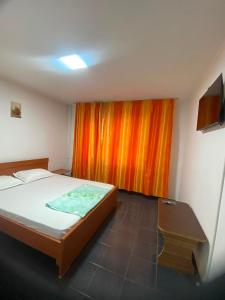 a bedroom with a bed and an orange curtain at Apartament Maria in Năvodari