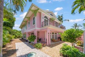 a pink house with a balcony at Waterfront Pink House with Private Dock & Pool in Captiva