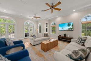 a living room with two couches and a tv at Waterfront Pink House with Private Dock & Pool in Captiva +30 photos