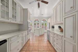 a kitchen with white cabinets and a tile floor at Waterfront Pink House with Private Dock & Pool in Captiva