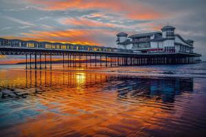 a pier with a building on the beach at sunset at Fairways - Flat 3 in Weston-super-Mare +5 photos