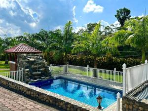 a swimming pool with a white fence and a fountain at Hosteria Arizona in Puyo