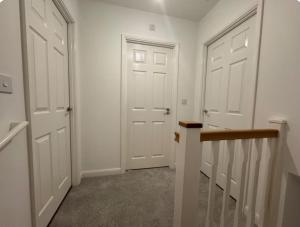 a hallway with two white doors and a staircase at Classic Foenix Home in Milton Keynes