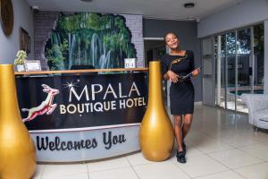 a woman standing next to a welcome sign at a hotel at Mpala Boutique Hotel in Bulawayo