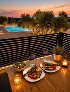 a table with two plates of food and glasses of wine at Luxury mobile home INES in Drage
