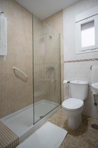 a bathroom with a toilet and a glass shower at Apartamentos Ortega in Tarifa
