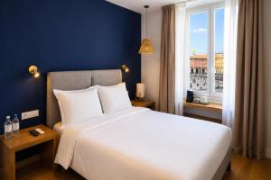 a bedroom with a large white bed and a window at Hotel De La Mer in Nice