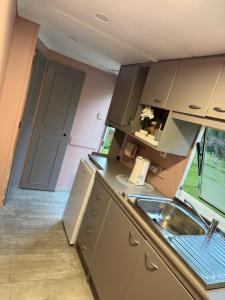 a small kitchen with a sink and a door at SeaSoul Cottage in Zvejniekciems +2 photos