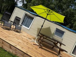a yellow umbrella and a bench on a deck at SeaSoul Cottage in Zvejniekciems