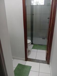 a bathroom with a shower and a toilet with green mats at Veneza Exclusive 101 in Ipatinga