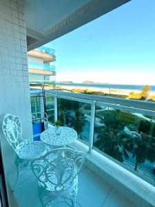 a balcony with two chairs and a view of the ocean at Mandai Apartamentos in Cabo Frio