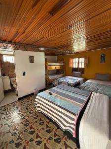 a bedroom with two beds and a wooden ceiling at Hospedaje El Encanto in Zipaquirá