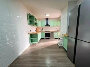 a kitchen with green cabinets and a refrigerator at Alma Andaluza Apart 1 in Mairena del Aljarafe