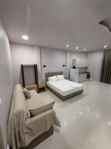 a white bedroom with a bed and a couch at Fatses in Nea Plagia