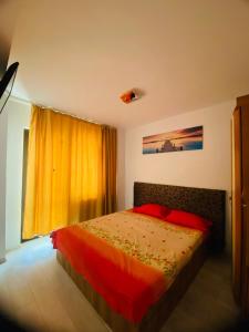 a bedroom with a bed with red pillows and a window at Apartament Daniela in Năvodari