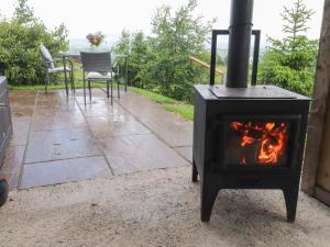 a stove on a patio with a table and chairs at The Journeyman Luxury Shepherds Hut in Barnoldswick