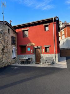a red building with a table and chairs in front of it at Ca el retriñon in Felechosa