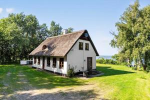 a white house with a brown roof on a grass field at LF11977-Struer-Norskovvej-17 in Vemb