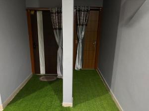 a room with green carpet and a door with curtains at RADHE RADHE HOMESTAy in Dithur +1 photo