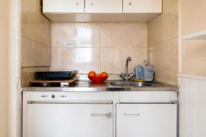 a kitchen with white cabinets and a sink at Alkyonis Apartments in Panormos Kalymnos
