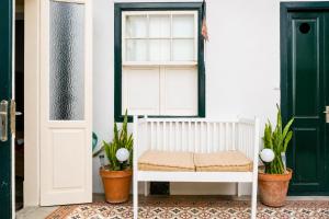a white bench in front of a door with plants at Casa Los Profesores, encanto tradicional canario en La Orotava in La Orotava