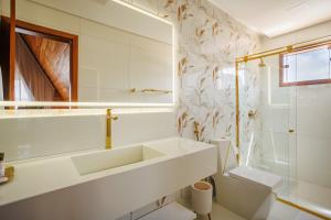 a white bathroom with a sink and a mirror at Pousada Recanto dos Chalés in Cruz +9 photos