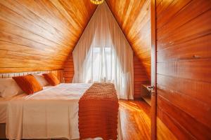 a bedroom with a bed with a wooden ceiling and a window at Pousada Recanto dos Chalés in Cruz