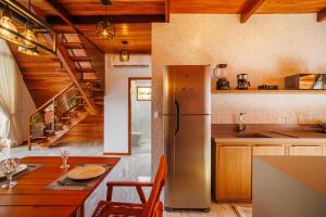 a kitchen with a stainless steel refrigerator and a table at Pousada Recanto dos Chalés in Cruz