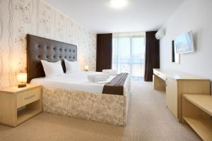 a hotel room with a large bed and a desk at La Piazza Primorsko Rooms & Apartments in Primorsko