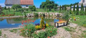 a park with a pond with flowers and a bench at Dom Skomackie Wzgórze widok na jezioro in Skomack Wielki