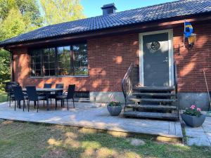 a house with a wooden deck with a table and chairs at Lilla lyckan in Skälsböke