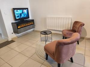 a living room with two chairs and a television at NEW! Appartement PrixMalin 1 à 7 personnes in Champagnole