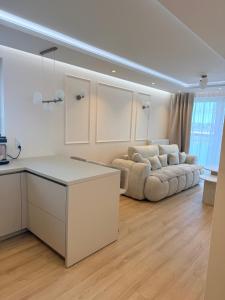 a kitchen and living room with a couch in the background at Apartament Baltic Pearl in Ustka