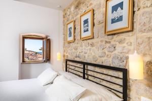 un dormitorio con una cama y una pared de piedra en Villa Four Winds, en Dubrovnik