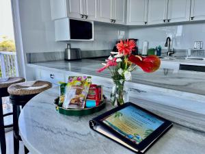 a tablet on a table in a kitchen with flowers at Puako Penthouse 409 - Top Floor Unit - Pool in Puako